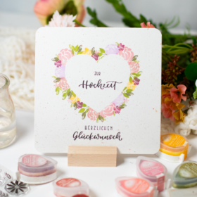 Selbstgemachte Hochzeitskarte mit Herz aus Blumen und dem Text „Herzlichen Glückwunsch zur Hochzeit“.
